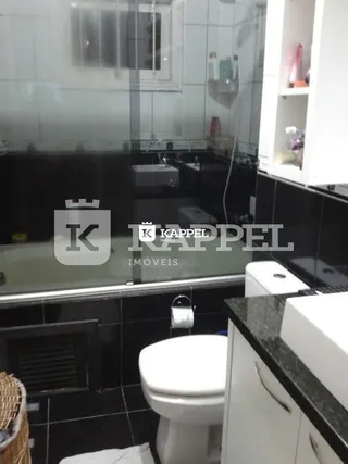 Foto de um banheiro com revestimento de azulejos brancos e um vaso sanitário.