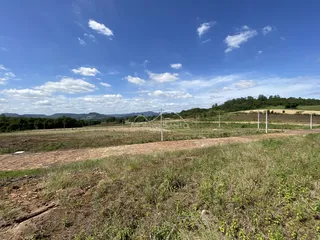 Vista panorâmica de uma paisagem rural com colinas verdes sob um céu azul.