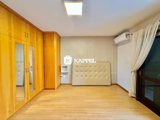 Sala de estar com armários de madeira e cabeceira estofada.