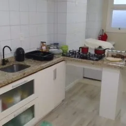 Uma cozinha com bancada e revestimento branco é visível na imagem.