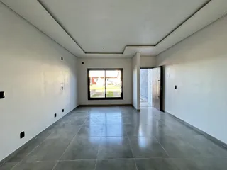 Interior de uma sala ampla com piso de cerâmica e grande janela.