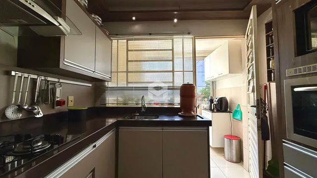 Vista da cozinha com armários de madeira e bancadas escuras.