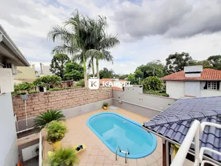 Piscina azul em área externa com vegetação tropical.
