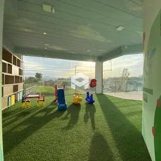 Área externa com gramado artificial e equipamentos de playground.