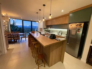 Ambiente de sala de jantar com vista para o mar e cozinha moderna.