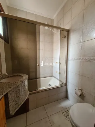 Foto de um banheiro com revestimento cerâmico e box de vidro.