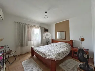 Quarto com cama de madeira e janela em um imóvel no Brasil.