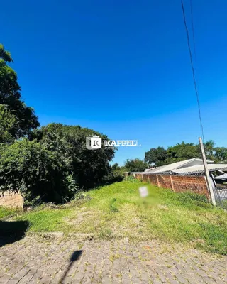 Vista externa do terreno com vegetação densa e céu azul.