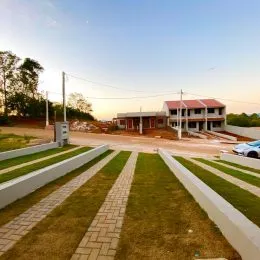 Área externa com gramado e bordas brancas em frente a uma edificação.