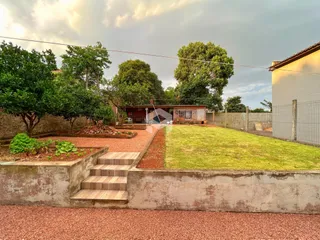 Vista externa da propriedade com jardim e muro de contenção.