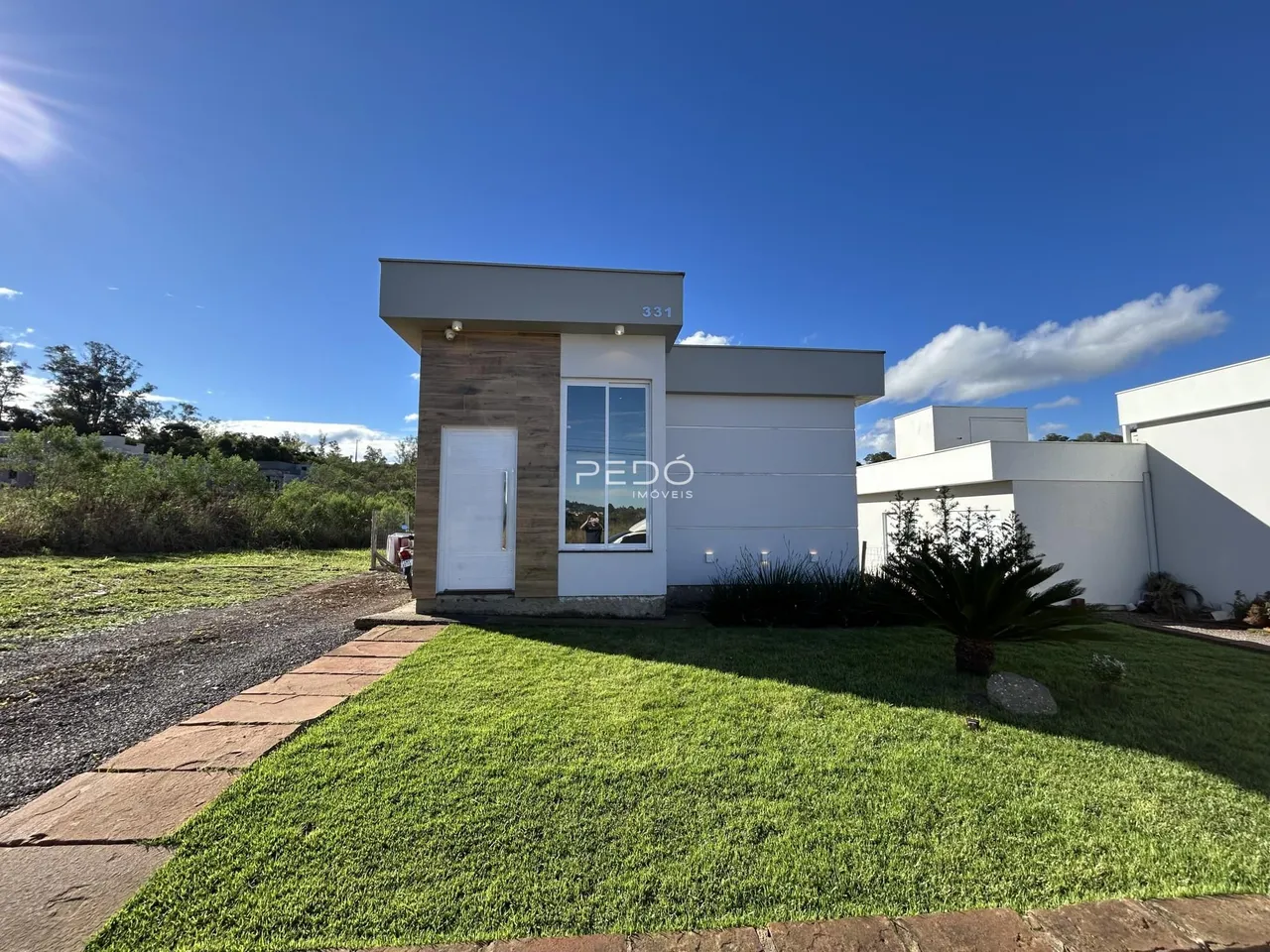 Fachada moderna de uma residência em Lajeado, Brasil, com jardim frontal.