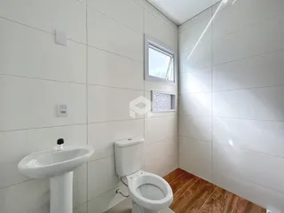 Foto de um banheiro com piso de madeira e paredes brancas.