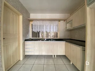Interior de uma cozinha com armários de madeira clara e janela.