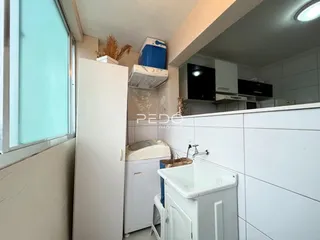 Vista interna de uma cozinha com bancada branca e janela.