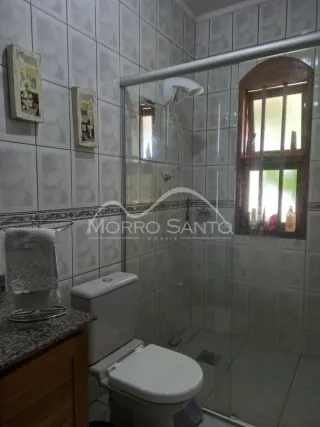 Banheiro com paredes de azulejos brancos e box de vidro transparente.