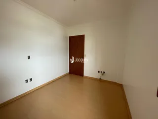 Hall de entrada com parede branca e piso de madeira.