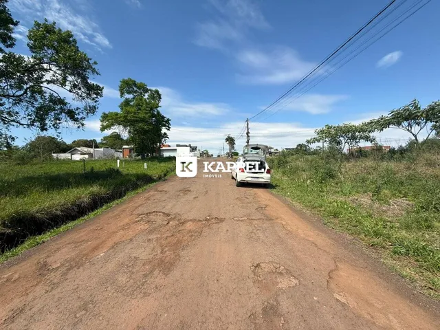 Uma estrada de terra leva a uma área rural sob um céu azul.