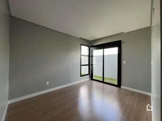 Interior de uma sala com piso de madeira e paredes cinzas.