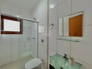Foto de um banheiro com revestimento cerâmico e box de vidro.