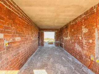 Corredor interno com paredes de tijolo aparente e piso de concreto.