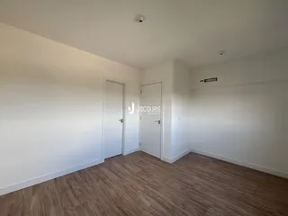 Corredor com paredes brancas e piso de madeira.