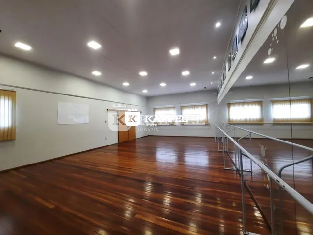 Foto de um cômodo amplo com piso de madeira polida e janelas.
