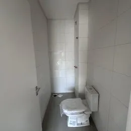 Foto de um corredor interno com paredes brancas e revestimento de azulejos brancos.