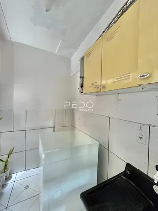 Interior de uma cozinha com armários amarelos e revestimento branco.