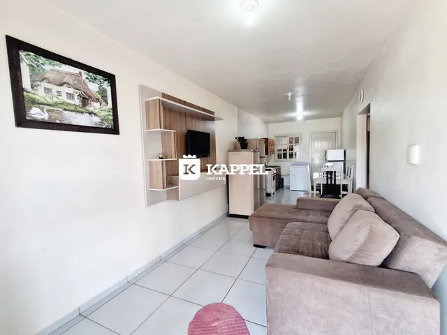 Sala de estar com sofá e área de cozinha em um apartamento em Lajeado.