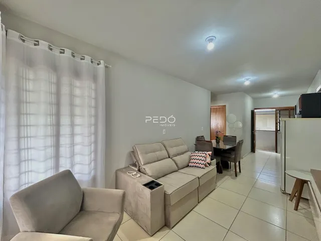 Foto de uma sala de estar com sofá e cortinas brancas.