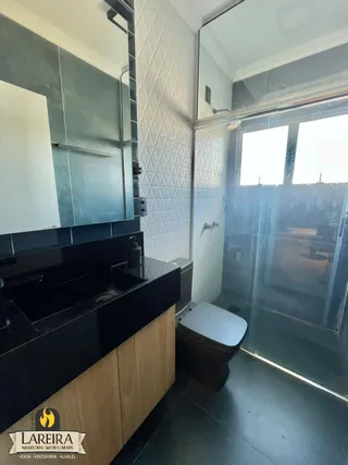 Interior de um banheiro com box de vidro e revestimento branco