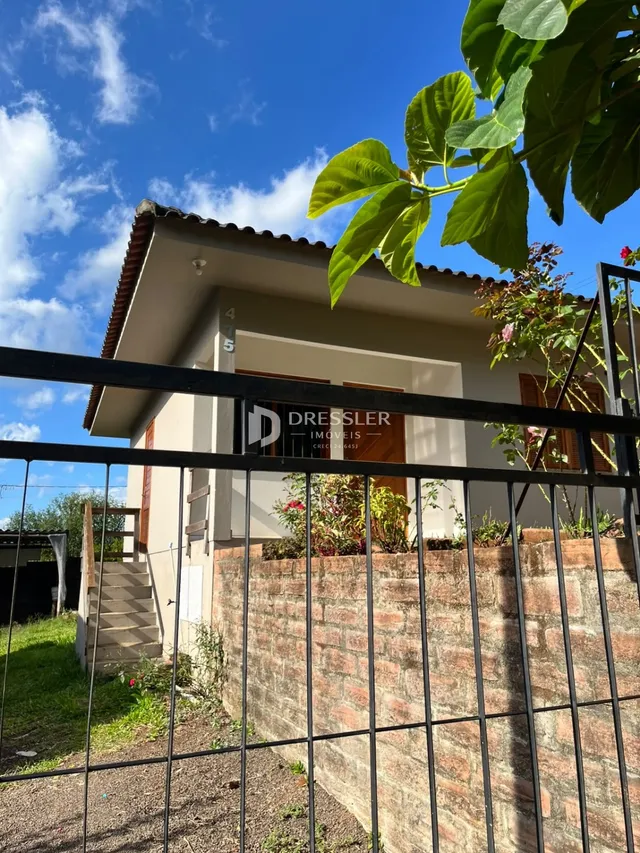 Vista externa de uma casa em Lajeado, Brasil, com muro de tijolos e grade de ferro.