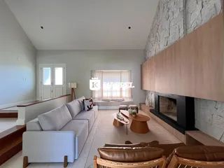 Sala de estar com sofá grande e lareira em ambiente claro.