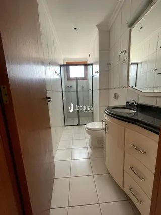 Hall de banheiro com piso cerâmico e box de vidro.