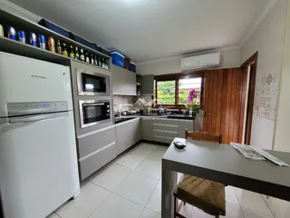 Interior de uma cozinha com armários brancos e eletrodomésticos em Lajeado.