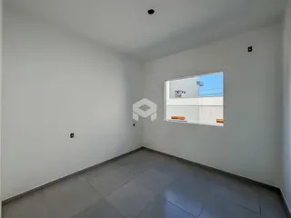 Interior de um ambiente com paredes brancas e piso de cerâmica cinza.