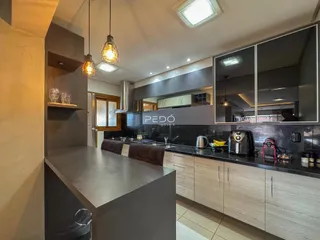 Vista da cozinha moderna com ilha e armários escuros.