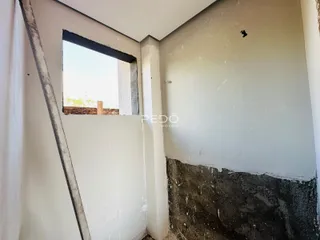 Parede interna com acabamento em concreto aparente e janela.