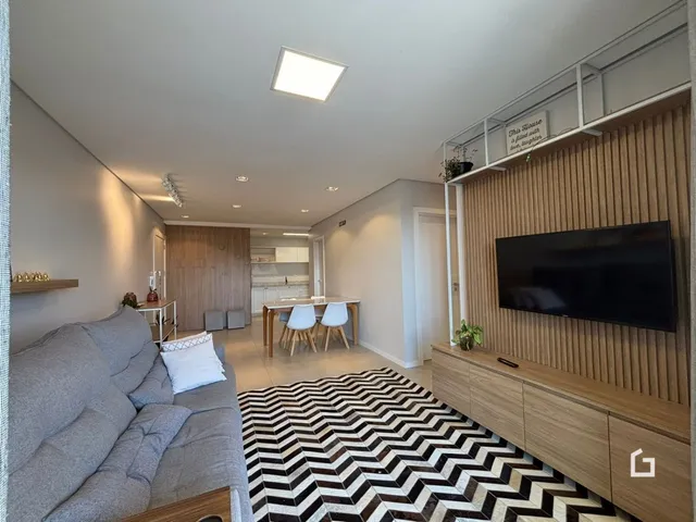 Sala de estar moderna com sofá cinza e piso geométrico.