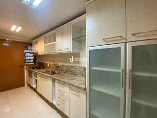Cozinha com armários brancos e bancadas de granito em um imóvel no Brasil.