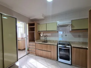 Uma cozinha com armários de madeira e bancada clara.