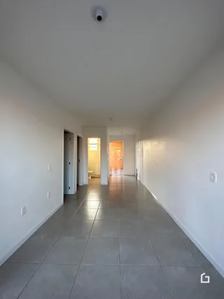 Corredor interno de uma residência com piso de cerâmica claro.