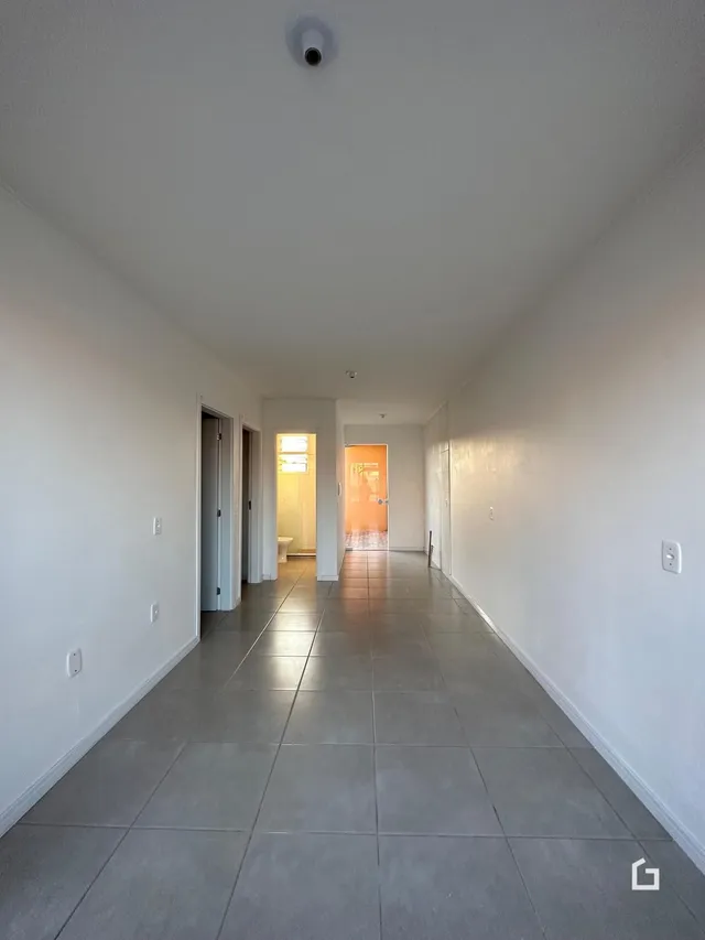 Corredor interno de uma residência com piso de cerâmica claro.