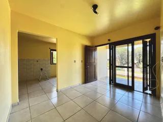 Uma sala interna com piso de cerâmica e portas de vidro que dão acesso ao exterior.