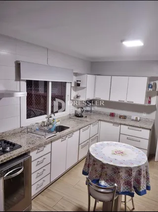 Cozinha moderna com armários brancos e bancadas claras.