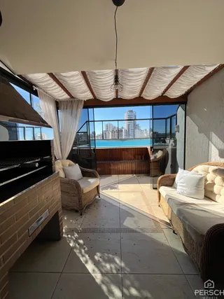 Vista de uma área externa com móveis de vime e estrutura de pergolado em um imóvel em Lajeado.