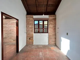 Interior de um corredor com parede de tijolos expostos e piso de cerâmica.