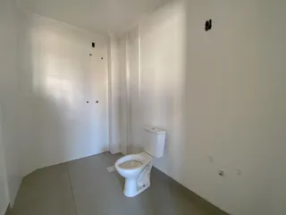 Foto de um banheiro interno com piso claro e vaso sanitário branco.