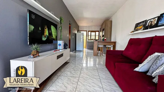 Sala de estar com sofá vermelho e televisão montada na parede.