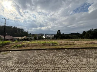 Paisagem de campo com vegetação e área pavimentada na frente da propriedade.